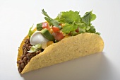 Taco with mince, avocado, sour cream and coriander leaves