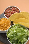 Tacos and filling ingredients (lettuce, cheese, salsa)