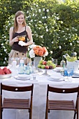 Woman with jug of iced tea by table laid in garden