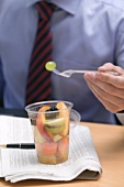 Geschäftsmann isst Fruchtsalat im Büro