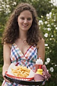 Woman holding tray of chips, ketchup and mustard