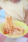 Small girl eating spaghetti with tomato sauce and Parmesan