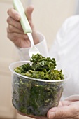 Woman eating cooked kale out of plastic tub