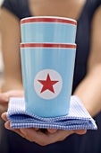Woman holding two paper cups with stars on checked cloth