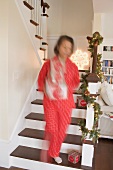 Frau trägt Schachteln mit Weihnachtsschmuck ins Wohnzimmer