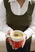 Frau hält Tasse Champignonsauce