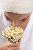 Woman smelling chamomile flowers