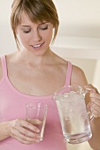 Woman pouring iced water into glass