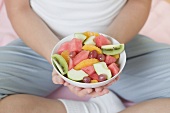 Seated woman holding dish of fruit salad