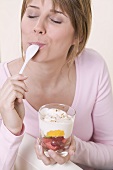 Frau isst Joghurtmüsli mit Früchten