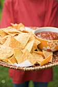 Person holding tray of nachos and salsa