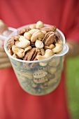 Person holding measuring jug full of mixed nuts