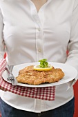 Woman holding plate of Wiener Schnitzel (veal escalope)