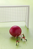 Radieschen mit Miniaturfussballspielern vor Fussballtor