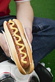 Fussballspieler hält Hot Dog mit Senf