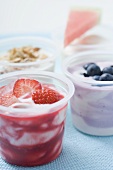 Four yoghurts with berries, cereal and watermelon