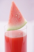 Wedge of watermelon on glass of watermelon juice