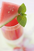 Wassermelonendrink mit Wassermelonenschnitz und Minzeblatt