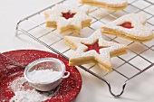 Jam biscuits on cake rack, icing sugar in sieve