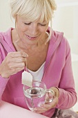 Woman putting tea bag into cup of hot water