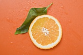 Slice of orange and leaf with drops of water