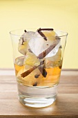 Rum and ice cubes with spices and pieces of fruit in glass