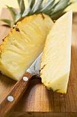 Wedges of pineapple on chopping board with knife