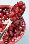 Half a pomegranate and spoonful of pomegranate seeds