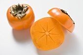 Two persimmons, one halved