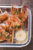 Salmon & prawn skewers with mint & sauce in aluminium dish