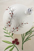White Christmas tree bauble on embroidered linen cloth