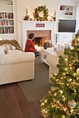 Woman by fireplace in living room decorated for Christmas