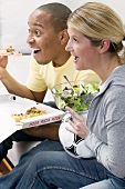 Couple in front of TV with pizza, salad and football