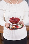 Frau hält Cranberrysauce in Glasschale (weihnachtlich)