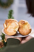 Hände halten Teller mit Popovers (weihnachtlich)