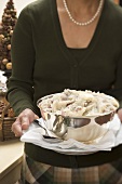 Woman holding mashed potato in silver bowl (Christmas)