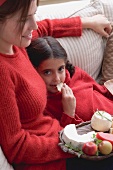 Woman and girl on sofa with cheeseboard and crackers