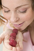 Woman smelling raspberries in her hand