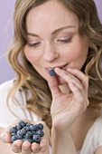 Woman tasting fresh blueberries