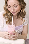 Woman holding glass of strawberry shake with straw