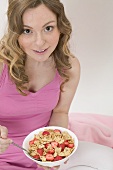 Woman eating cornflakes with strawberries