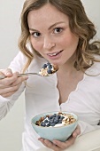 Woman eating muesli with blueberries