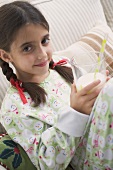 Girl holding glass of milk with straw