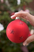 Hand holding red Christmas bauble