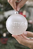 Hands holding white Christmas bauble