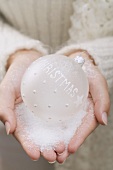 Hands holding white Christmas bauble