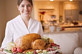 Young woman serving roast turkey on platter
