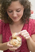 Woman taking almond biscuit out of glass