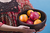 Woman holding fresh fruit in wooden bowl