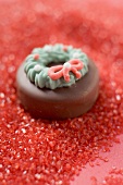 Weihnachtliche Schokoladenpraline auf rotem Zucker